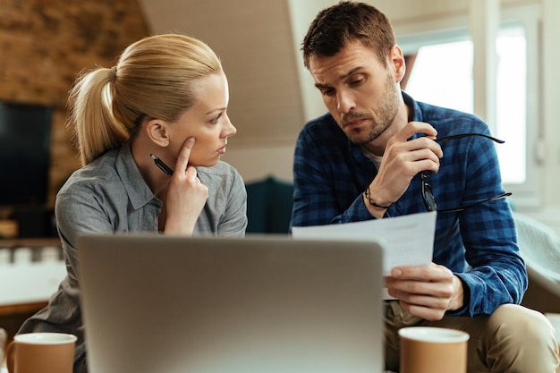 Jeune couple communiquant tout en passant par leurs finances à la maison