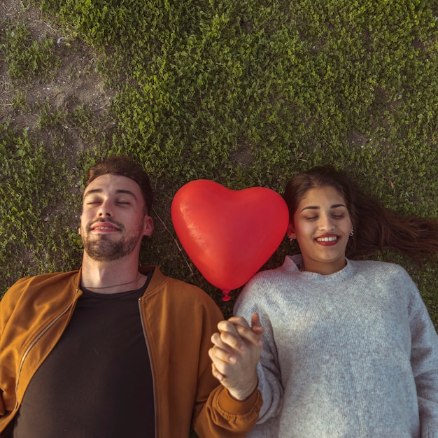 Photo gratuite jeune couple, coucher herbe, à, ballon coeur