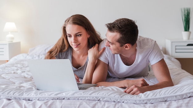 Jeune couple, coucher lit, à, ordinateur portable