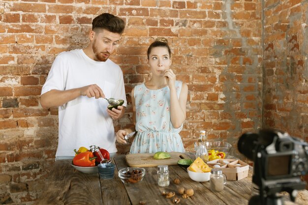 Jeune couple cuisinant ensemble et enregistrant une vidéo en direct pour vlog