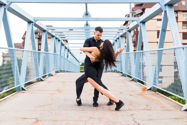 Photo gratuite jeune couple dansant le tango sur le pont