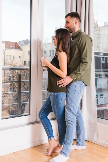 Photo gratuite jeune couple debout près de la vitre