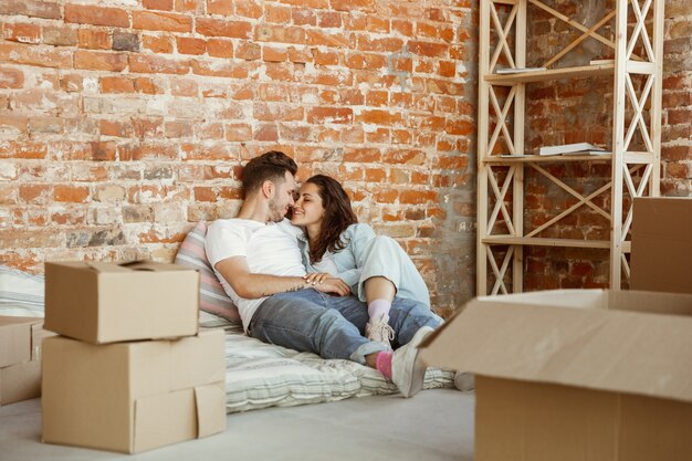 Jeune couple a déménagé dans une nouvelle maison ou un nouvel appartement. Allongé ensemble, se détendre après le nettoyage et le déballage le jour du déménagement