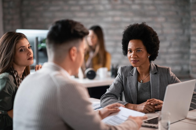 Jeune couple discutant avec leur conseiller financier de leurs futurs investissements L'accent est mis sur le conseiller financier de l'Amérique africaine