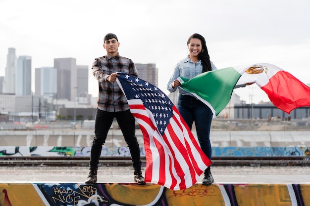 Photo gratuite jeune couple avec des drapeaux à côté de la rivière