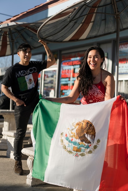 Photo gratuite jeune couple avec des drapeaux mexicains dans la rue