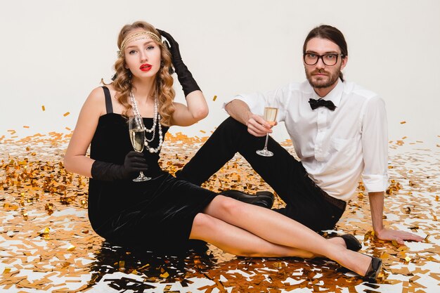 Jeune couple élégant amoureux, assis sur le sol entouré de confettis dorés