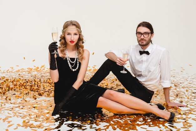 Jeune couple élégant amoureux, assis sur le sol, jetant des confettis dorés