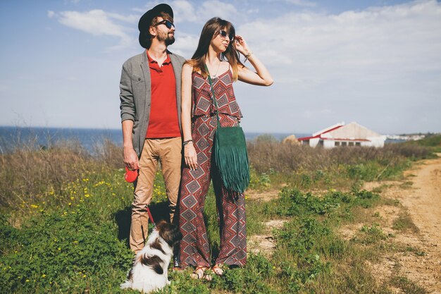 Jeune couple élégant hipster amoureux marchant avec un chien dans la campagne