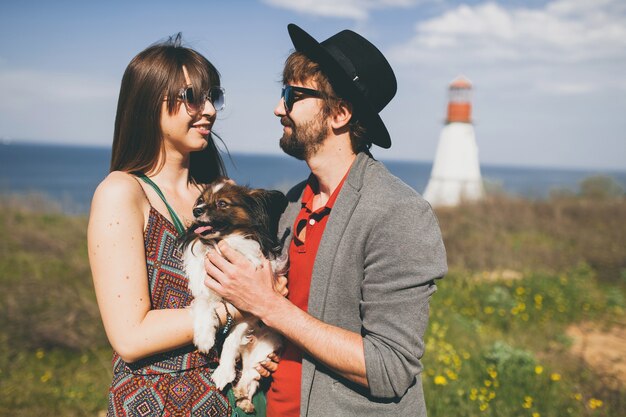 Jeune couple élégant hipster amoureux marchant avec un chien dans la campagne