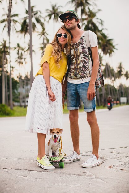 Jeune couple élégant hipster amoureux en vacances avec chien et planche à roulettes, s'amuser