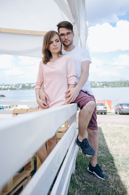 Jeune couple embrassant et assis sur une clôture blanche