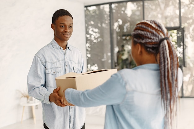 Photo gratuite jeune couple emménageant dans une nouvelle maison ensemble. couple afro-américain avec des boîtes en carton.