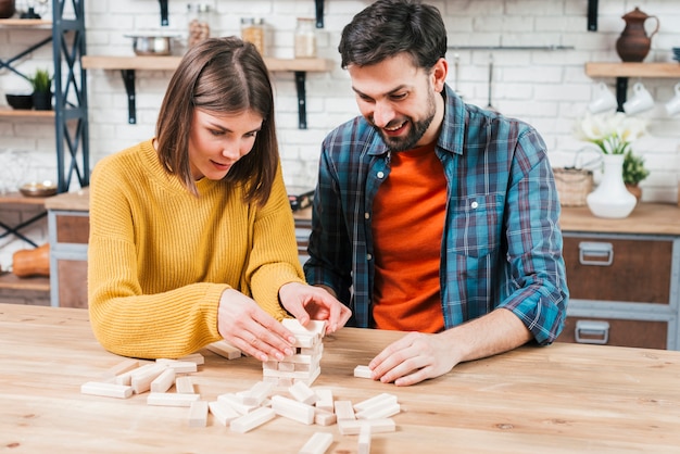 Jeune couple empiler le bloc de bois sur la table dans la cuisine