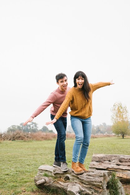 Jeune couple, équilibre, sur, tronc arbre