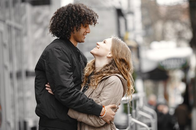 Jeune couple étreignant dans la rue portant des manteaux.