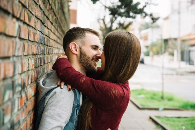 Jeune couple, étreindre, devant, mur brique