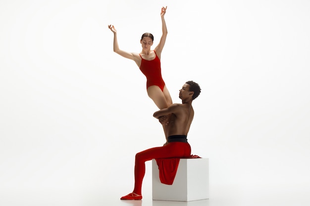 Jeune couple gracieux de danseurs de ballet dansant sur fond de studio blanc