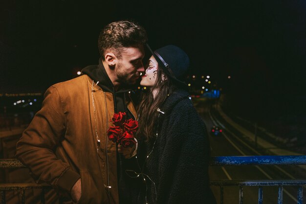 Jeune couple en guirlande s&#39;embrassant dans une rue sombre