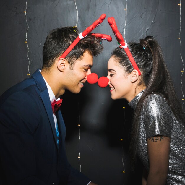 Photo gratuite jeune couple heureux avec bandeaux en bois de cerf rouge et nez drôle