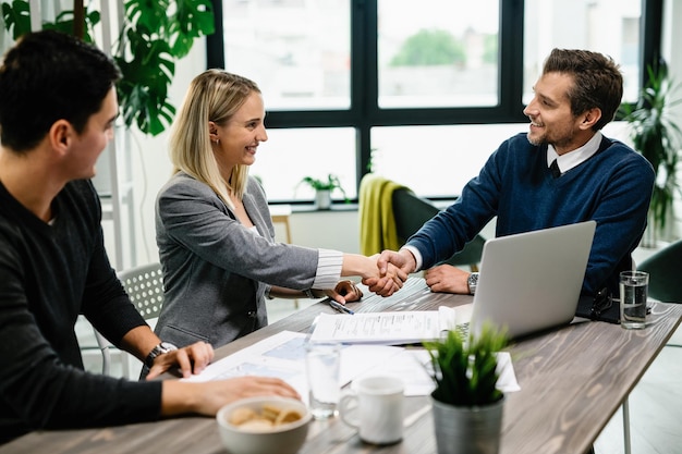 Photo gratuite jeune couple heureux rencontre un conseiller financier au bureau la femme est la poignée de main avec l'agent