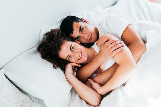 Jeune couple heureux sous la couette sur le lit