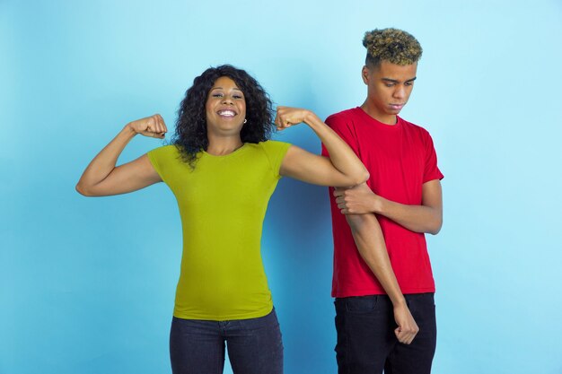 Jeune couple heureux en vêtements décontractés posant sur le mur bleu