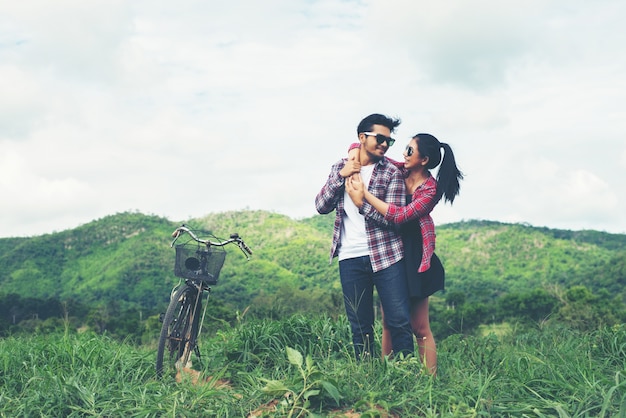 Jeune couple hippie tenant la main marchant sur la prairie relaxine