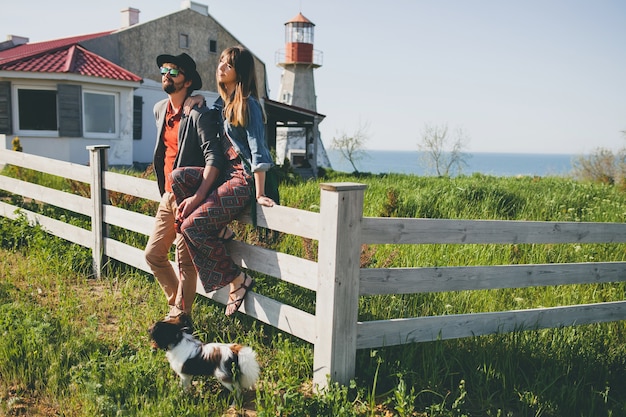Jeune couple de hipster élégant amoureux marchant avec chien dans la campagne, mode boho de style été