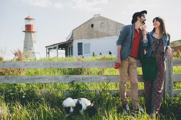 Jeune couple hipster élégant amoureux marchant avec un chien dans la campagne