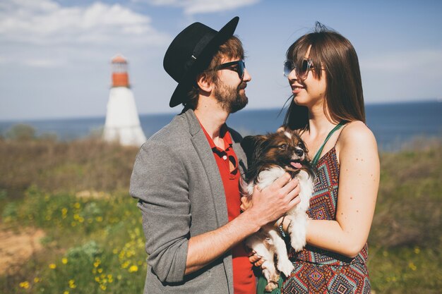 Jeune couple hipster élégant amoureux marchant avec un chien dans la campagne