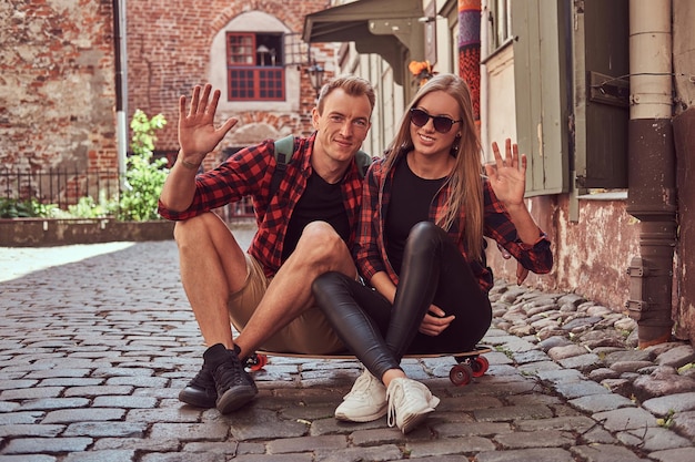 Jeune couple hipster heureux, se reposer pendant une promenade assis sur le trottoir dans la vieille rue de l'Europe.