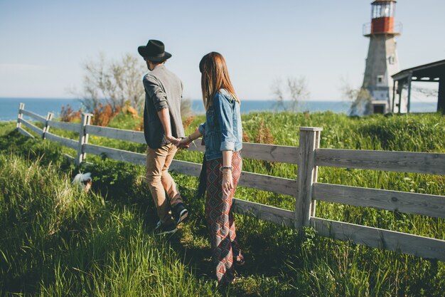 Jeune couple hipster style indie amoureux marchant dans la campagne, main dans la main