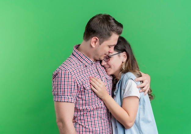 Jeune couple, homme femme, dans, vêtements décontractés, heureux, amoureux, étreindre, debout, sur, mur vert