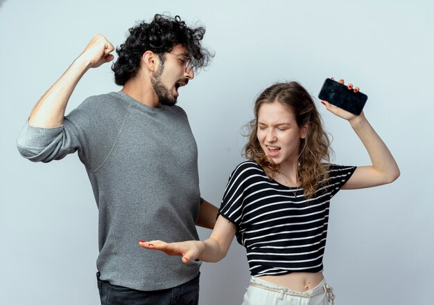 Photo gratuite jeune couple homme et femme se quereller en criant les uns les autres debout sur un mur blanc