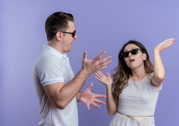 Photo gratuite jeune couple homme et femme se quereller gesticulant avec les mains sur le bleu