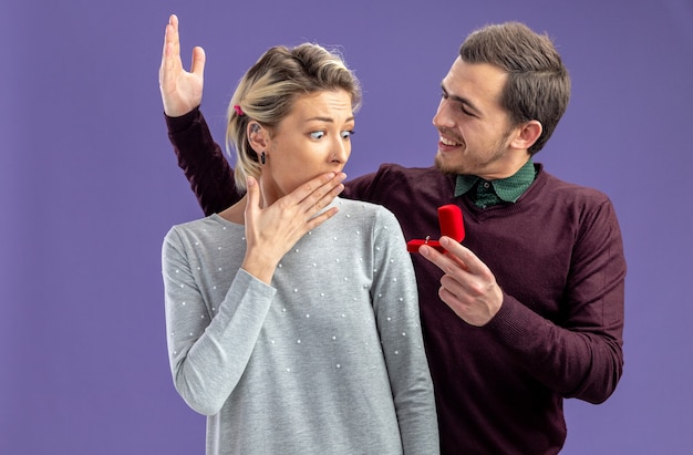 Jeune Couple Le Jour De La Saint-valentin Mec Excité Donnant Une Bague De Mariage à Une Fille Surprise Isolée Sur Fond Bleu