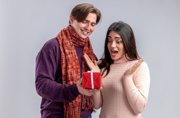 Jeune couple le jour de la Saint-Valentin souriant gars donnant une boîte-cadeau à une fille surprise isolée sur fond blanc