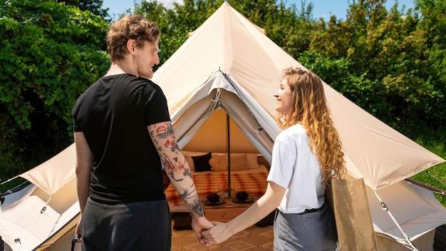 Jeune couple main dans la main près de la tente au glamping. verdure autour