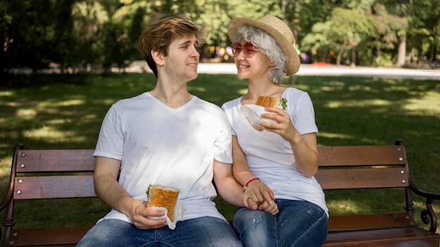 Jeune couple, manger, hamburgers, dans parc