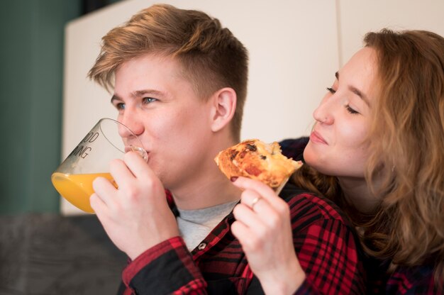 Jeune couple, manger pizza, chez soi