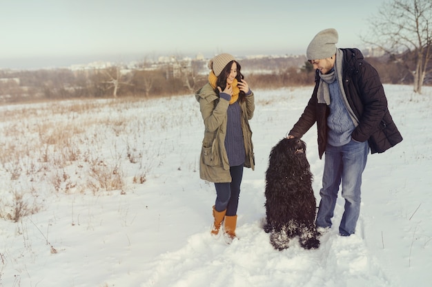 Jeune couple marchant avec un chien dans une journée d'hiver