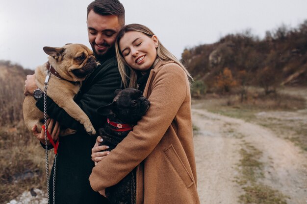 Jeune couple marchant leurs bouledogues français dans le parc