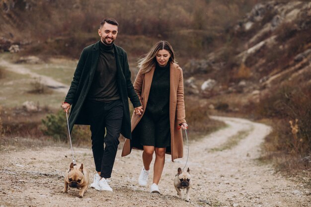 Jeune couple marchant leurs bouledogues français dans le parc