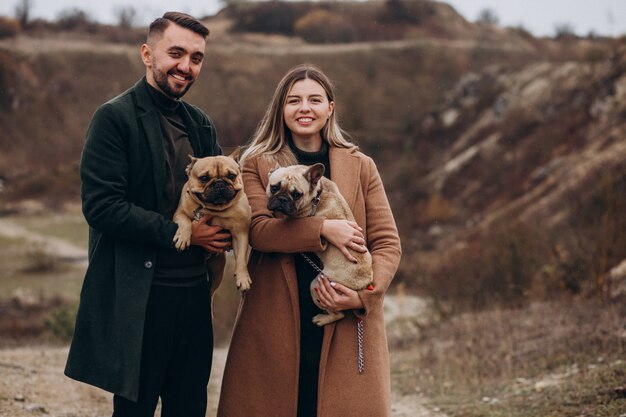 Jeune couple marchant leurs bouledogues français dans le parc