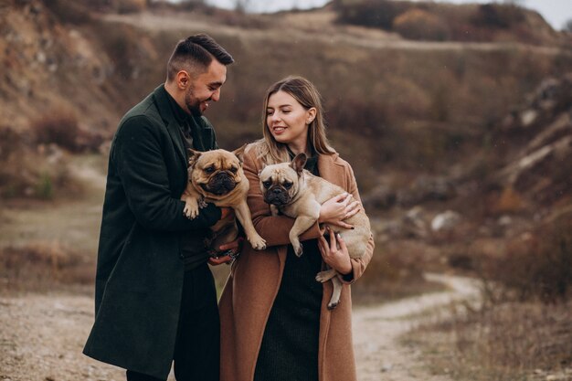 Jeune couple marchant leurs bouledogues français dans le parc