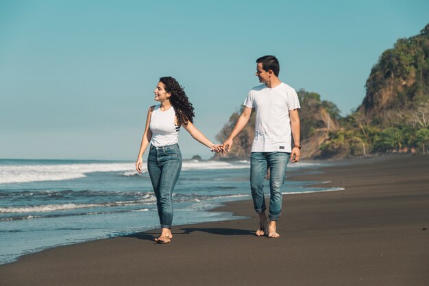 Jeune couple marchant le long de la plage déserte