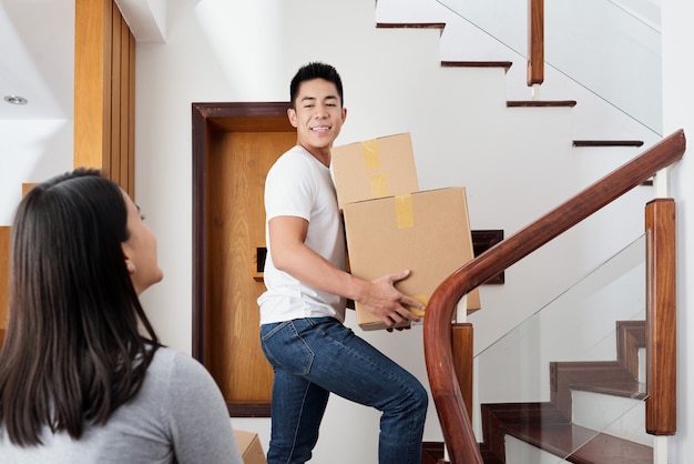 Jeune couple métisse apportant des boîtes en carton dans leur nouvel appartement