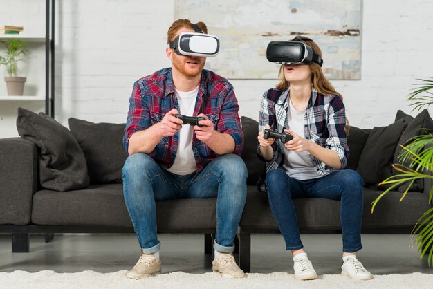 Jeune couple portant des lunettes de réalité virtuelle jouant au jeu vidéo dans le salon