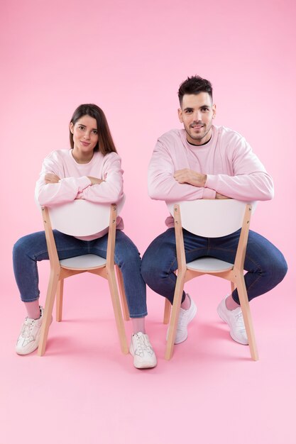 Jeune couple portant des vêtements semblables sur des chaises
